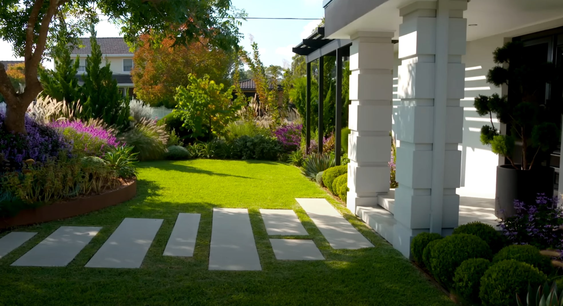 Contemporary Landscape Design featuring Hardscaping and Colorful Plant Selections Elegant modern garden with concrete pavers, lush lawn, and colorful flowering plants