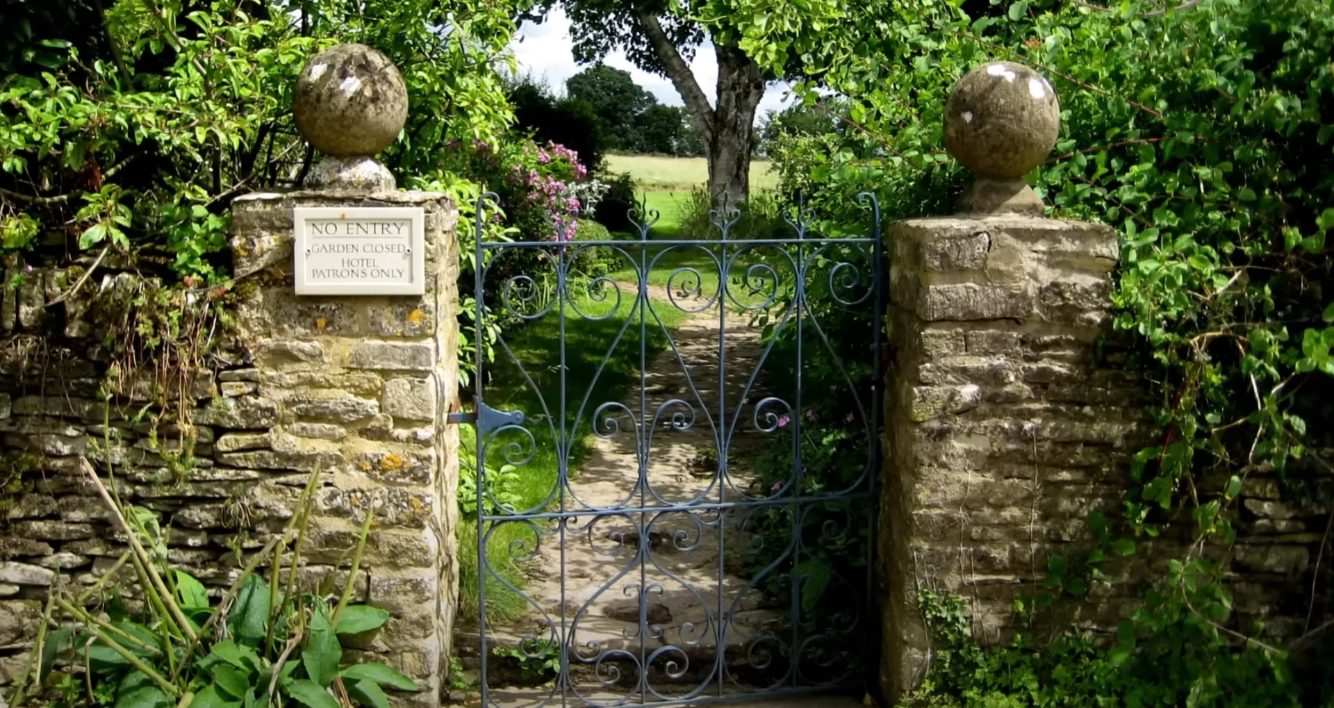 Custom Hardscaping - Stone Entrance Gates and Garden Design Traditional stone garden entrance with decorative iron gates and mature landscaping design